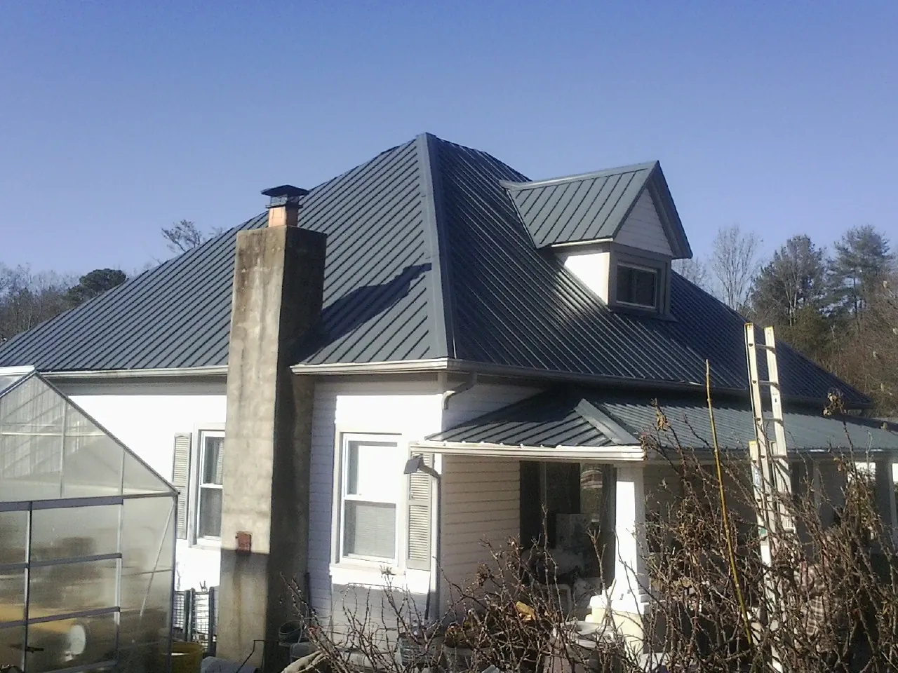 Dark blue standing seam metal roof on a white farmhouse with dormer — Slate & Tile Roof Repair by Roofing Brothers in Turners Falls