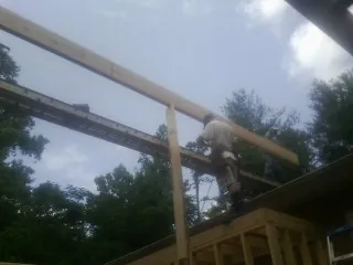 Carpenter setting a ridge beam over a new addition frame — Ice Dam Removal by Roofing Brothers in Turners Falls