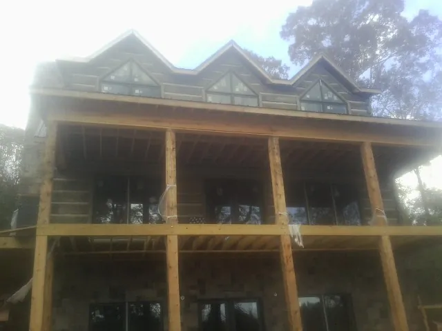 Dormers and porch framing on a large log home under construction — Roof Coating work by our crew in Turners Falls