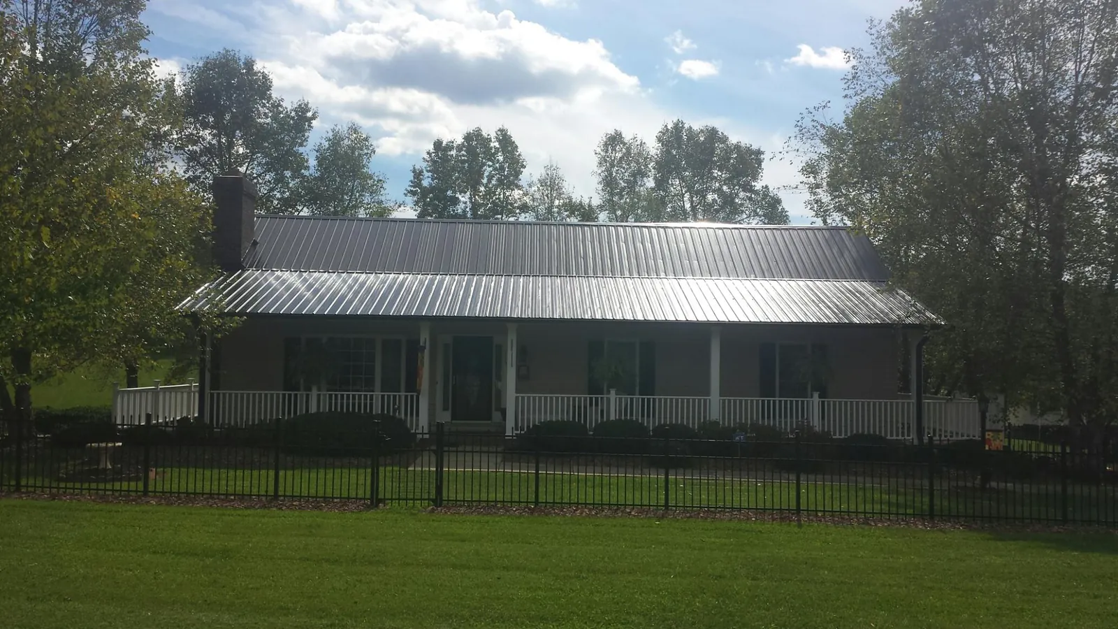 Gray metal roof on a brick ranch with a full width front porch — Gutter Guard Installation work by our crew in Turners Falls