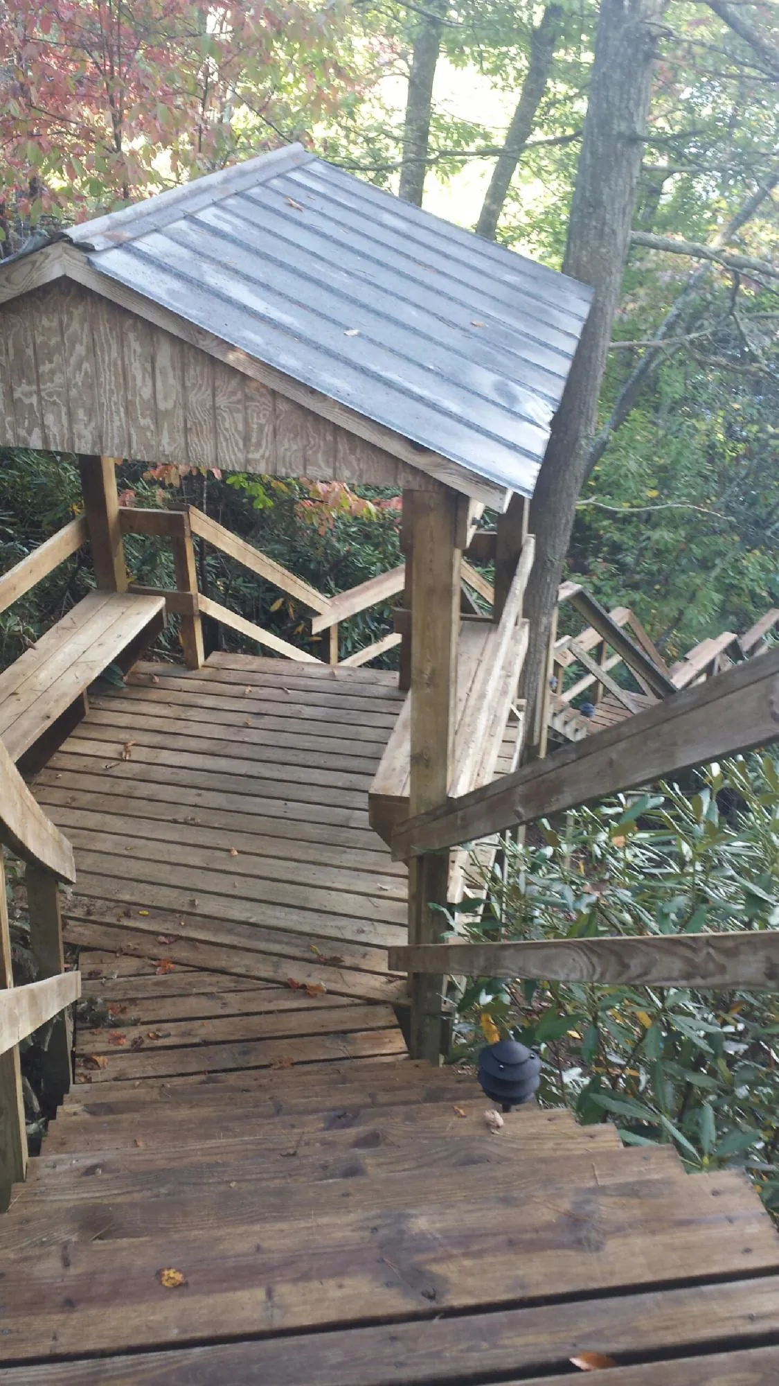 Metal roofed shelter over wooden steps on a wooded walkway — Skylight Repair & Installation work by our crew in Turners Falls