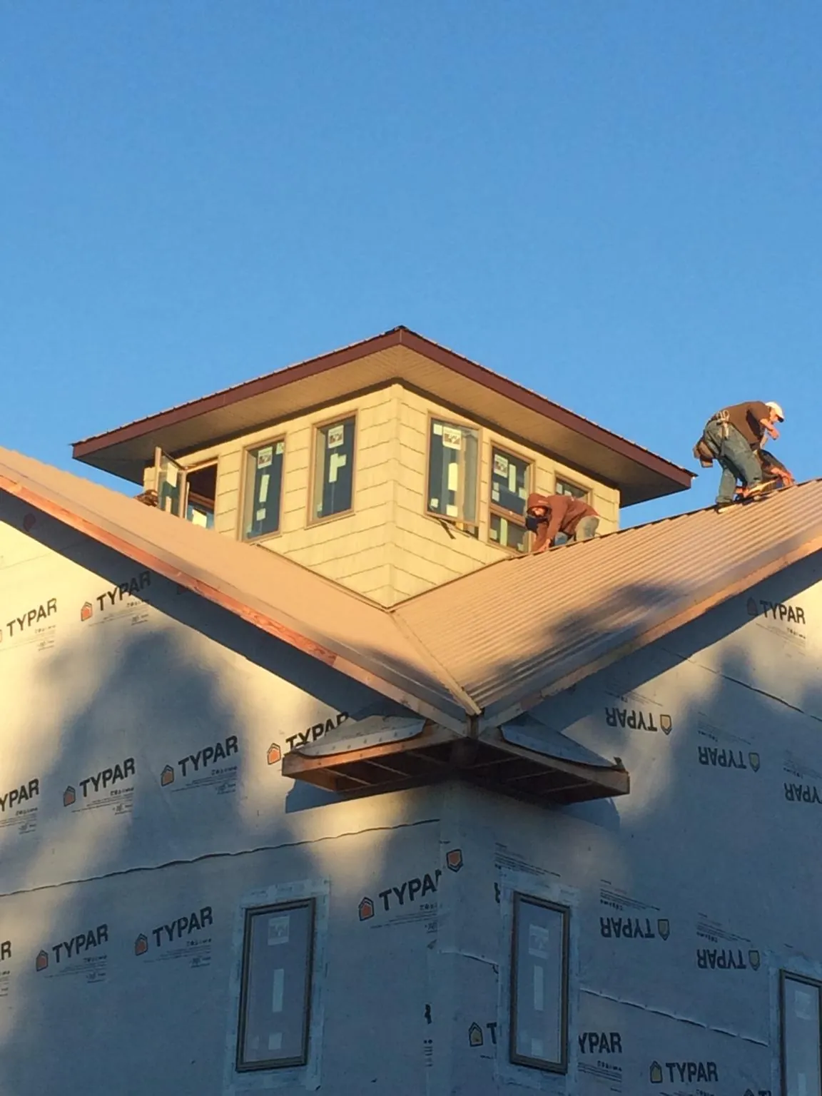 Roofers working around a rooftop cupola on a new metal roof at sunset — Roof Waterproofing in Turners Falls by Roofing Brothers